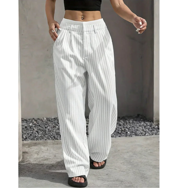 Woman wearing white pinstripe wide-leg pants, black crop top, and sandals outdoors for Rovelli