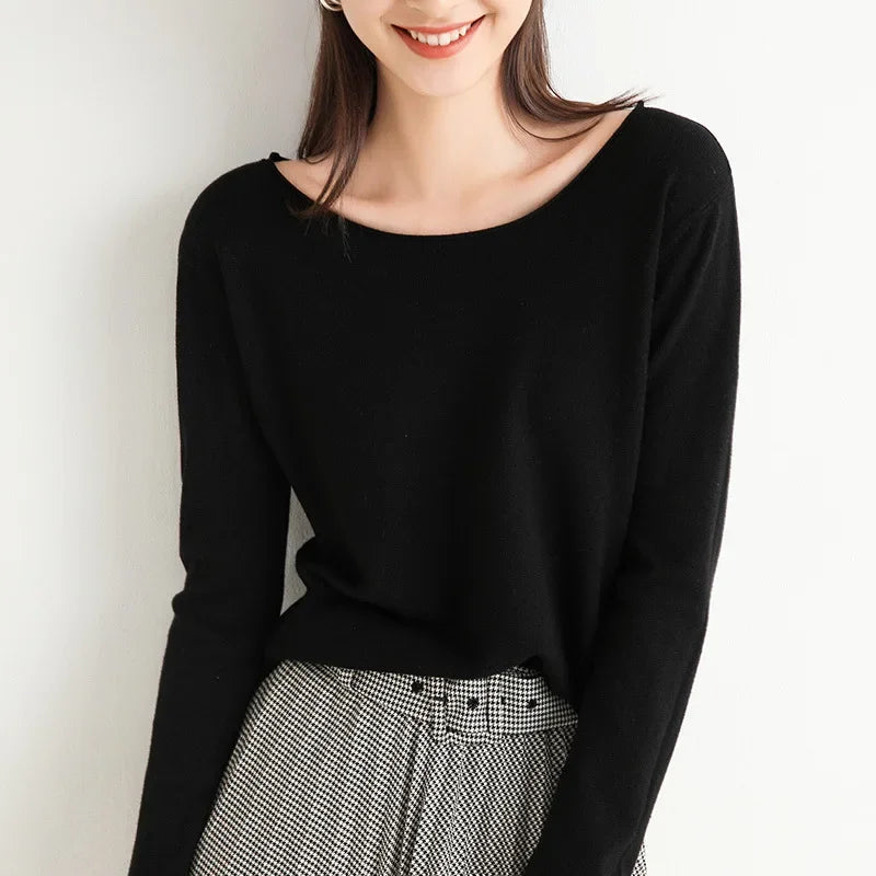 A woman wearing a black cashmere blend long-sleeve top and high-waisted black-and-white checkered pants with a relaxed fit stands against a white background, smiling with her hair down. Her face is partially visible.