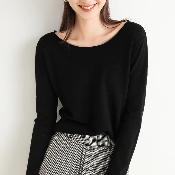 A woman wearing a black cashmere blend long-sleeve top and high-waisted black-and-white checkered pants with a relaxed fit stands against a white background, smiling with her hair down. Her face is partially visible.