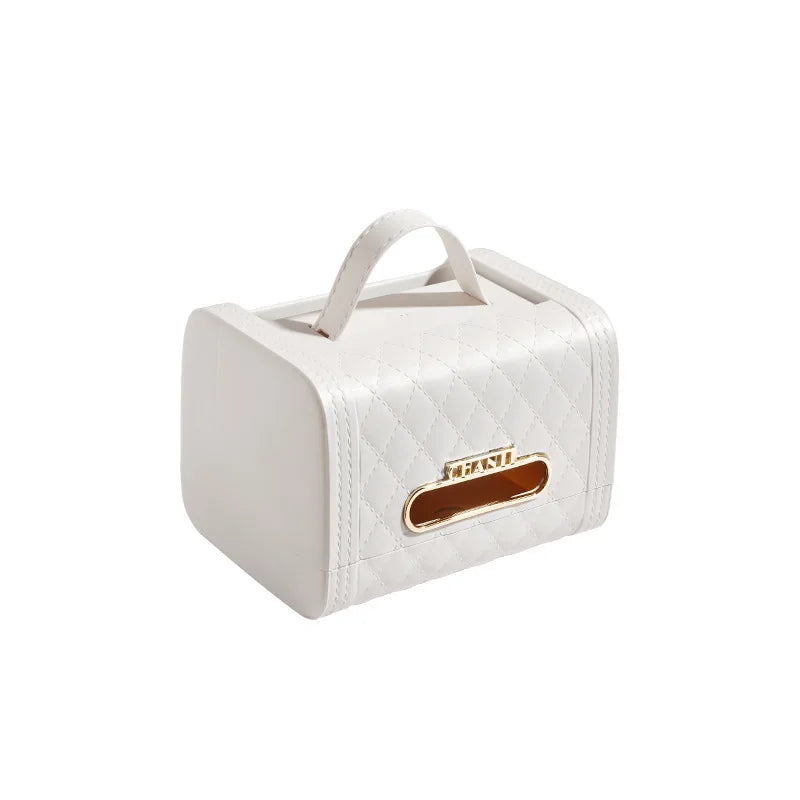 A white, quilted tissue box cover with a handle on top and a gold-edged opening for dispensing tissues, this elegant storage solution enhances your home decor against a plain white background.