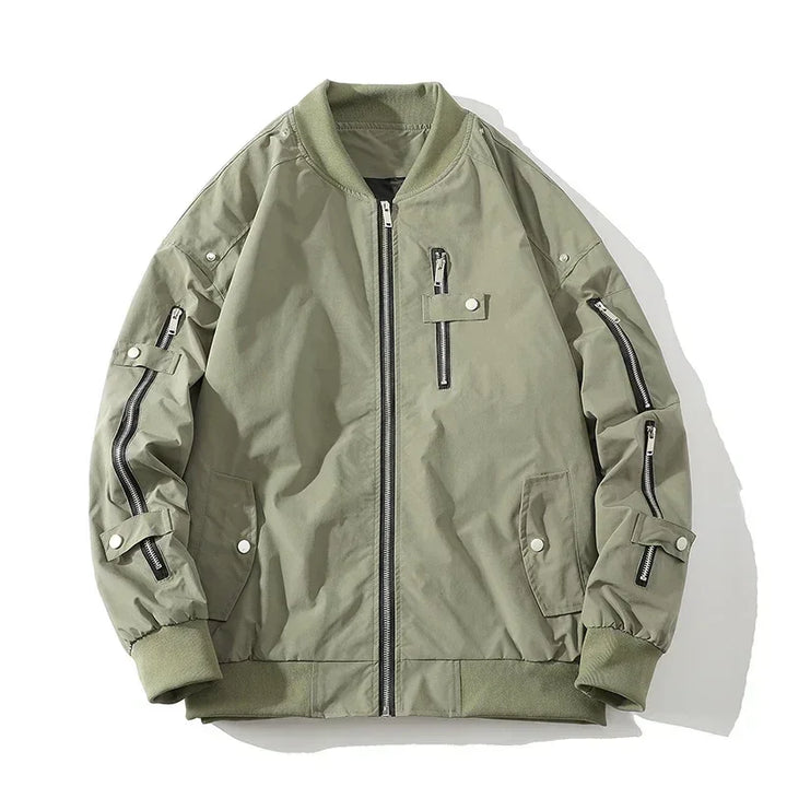 A light olive green bomber jacket with a ribbed collar, black zipper closures, zippered chest and sleeve pockets, buttoned side pockets, and ribbed cuffs and waistband, laid flat on a white background.