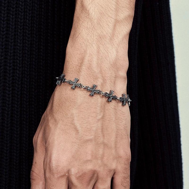 Rovelli silver cross chain bracelet on wrist, black ribbed fabric background