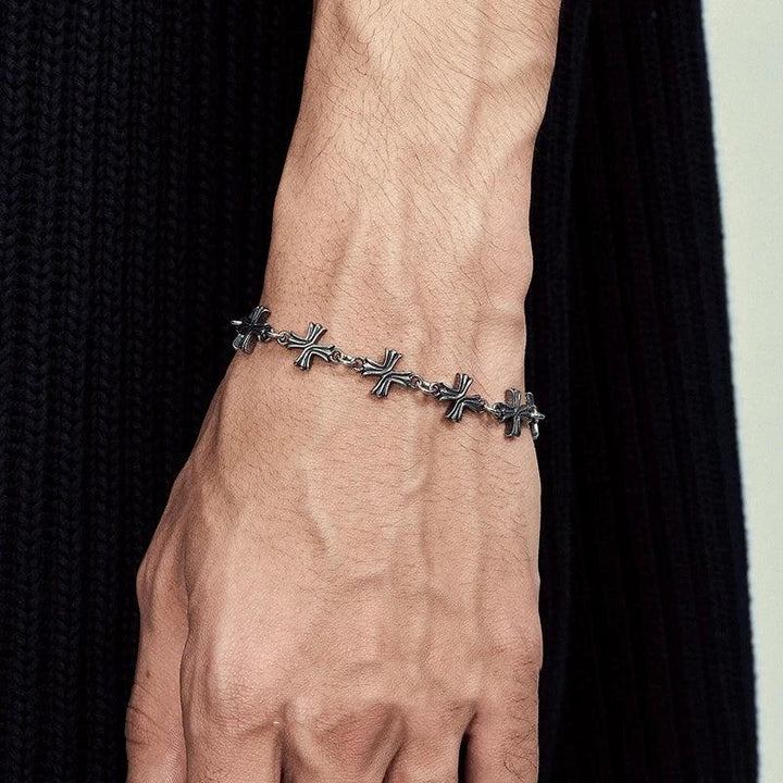 Rovelli silver cross chain bracelet on wrist, black ribbed fabric background