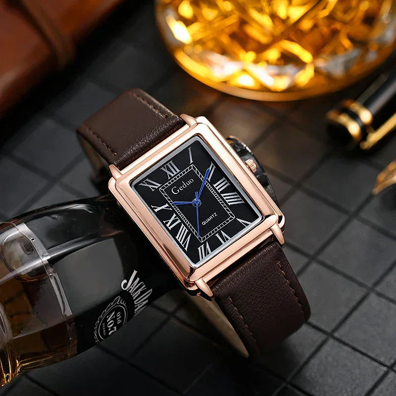 A rectangular luxury watch with a black face, Roman numerals, blue hands, and a brown premium leather band rests on a glass bottle beside a crystal glass on a black tiled surface.