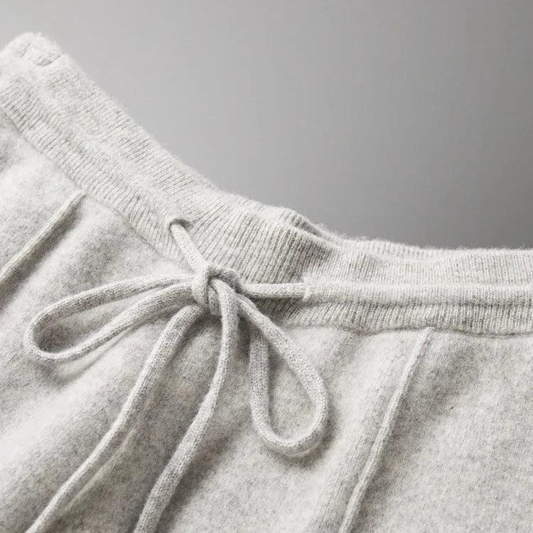 Close-up of the waistband of light gray sweatpants made from soft, textured fabric, featuring a drawstring tied in a bow—these comfortable pants offer both style and durable construction.
