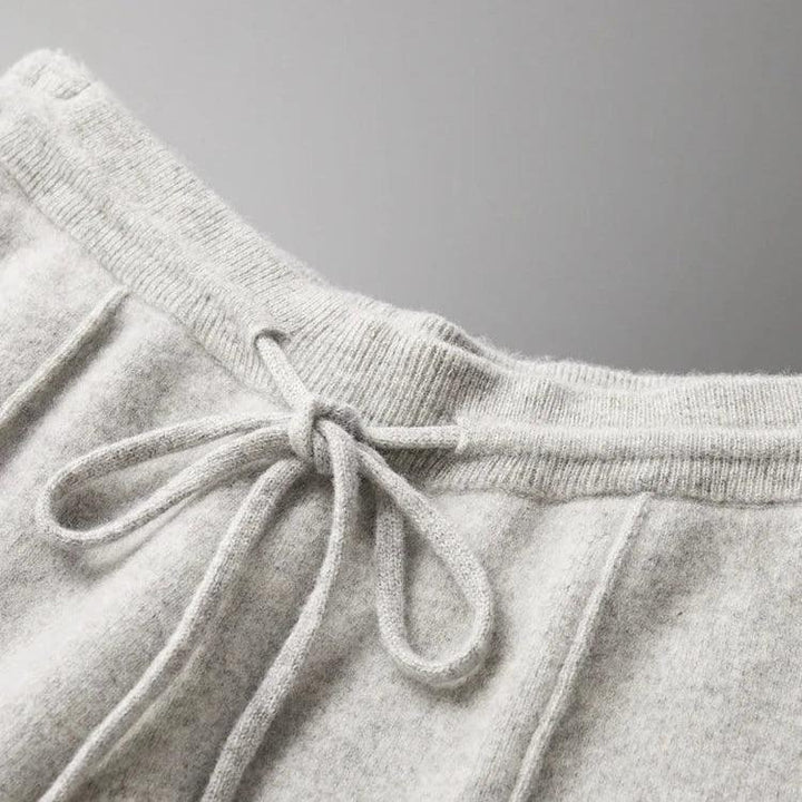 Close-up of the waistband of light gray sweatpants made from soft, textured fabric, featuring a drawstring tied in a bow—these comfortable pants offer both style and durable construction.