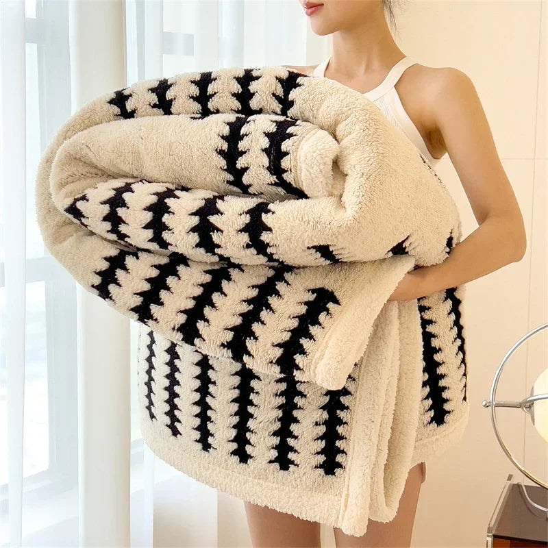 Woman holding a thick, fluffy black and white patterned blanket in bright room, Rovelli home