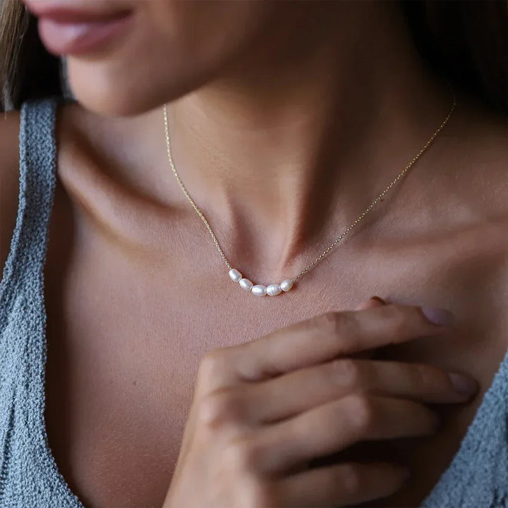 Woman wearing Rovelli gold chain necklace with five freshwater pearls