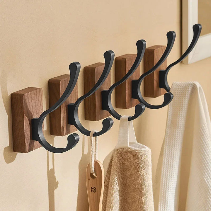 Modern wall-mounted wooden coat hooks with black metal accents in a home entryway, Rovelli