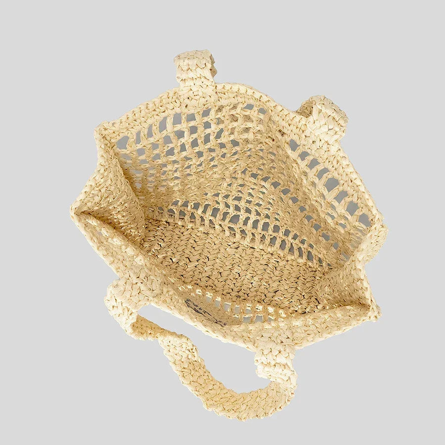 Rovelli woven straw tote bag with open mesh design and handles on light gray background