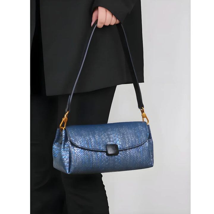 Person holding a Rovelli blue textured leather handbag with gold hardware