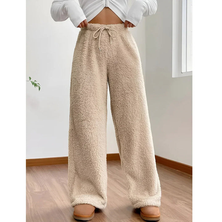 Beige sherpa fleece lounge pants with drawstring waist, modeled indoors on wood floor, Rovelli