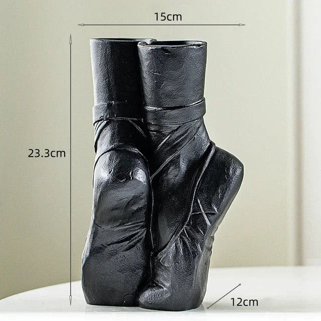 Black ceramic vase shaped like ballet shoes standing on tiptoe, 23.3 cm tall, 15 cm wide, and 12 cm deep. This ballet-inspired vase adds contemporary chic décor to any space, displayed on a white surface against a neutral background.