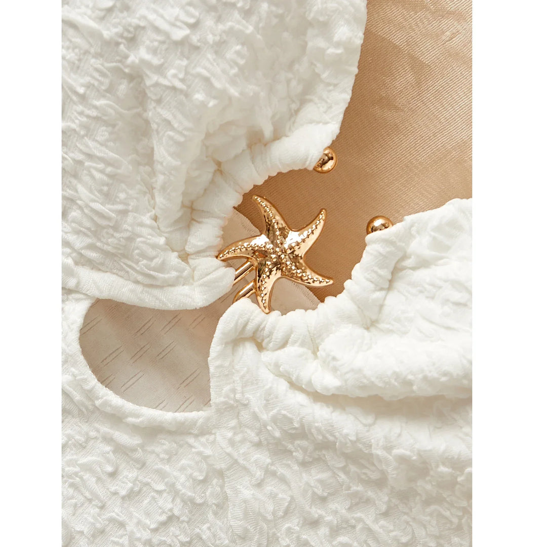 Textured white fabric with a gold starfish detail, Rovelli fashion accessory close-up