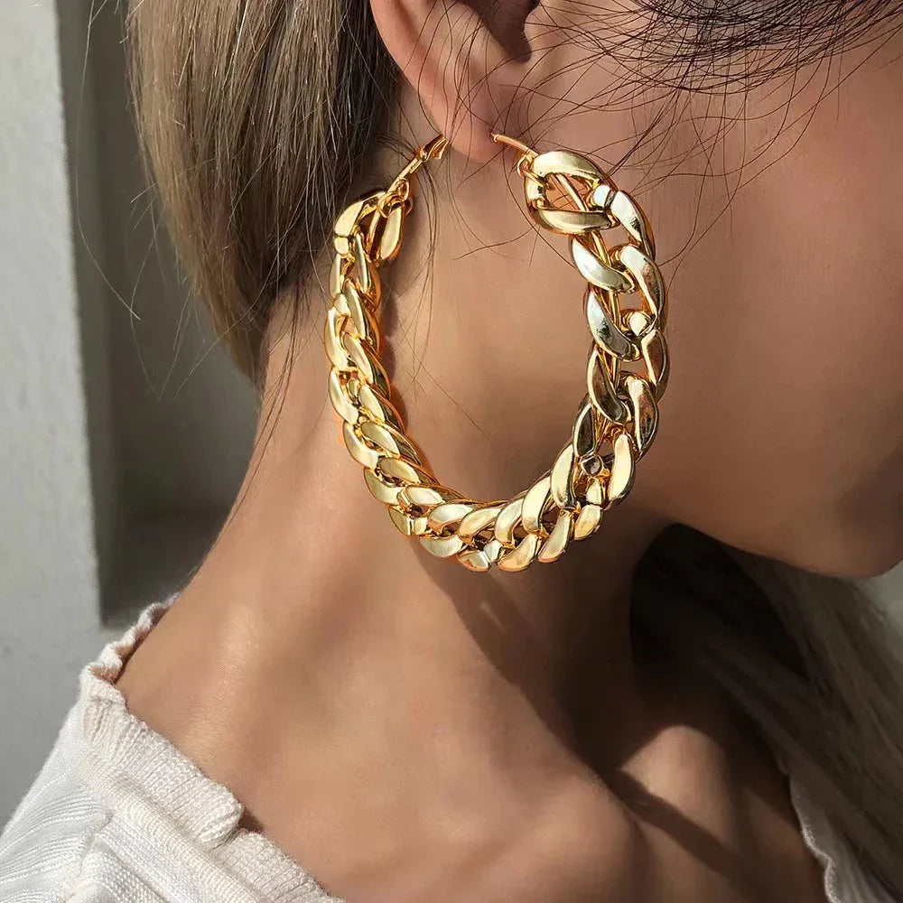 Rovelli chunky gold hoop chain earring on woman's ear, modern jewelry closeup
