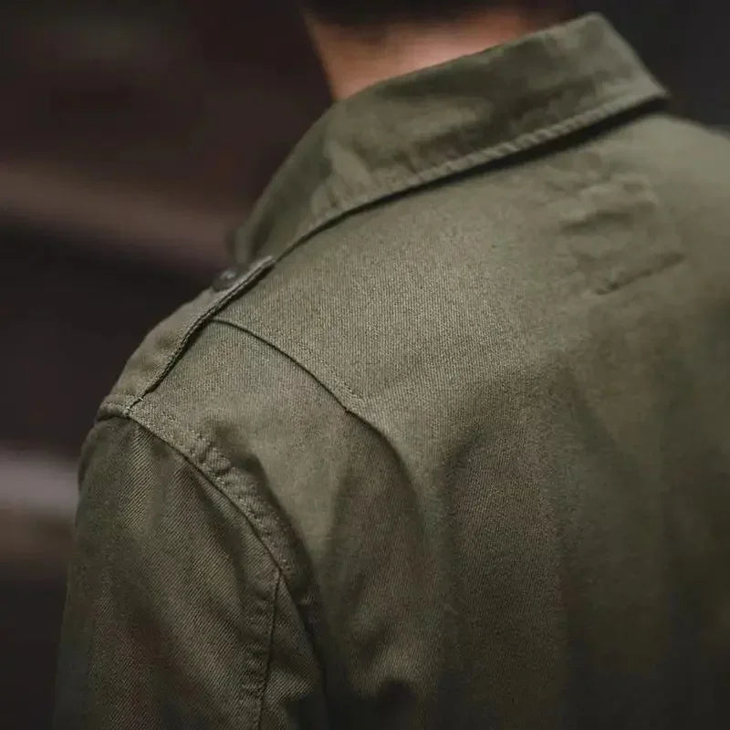 Close-up view of the back and shoulder of a person wearing an olive green collared tactical jacket, focusing on the fabric texture and precise stitching details.