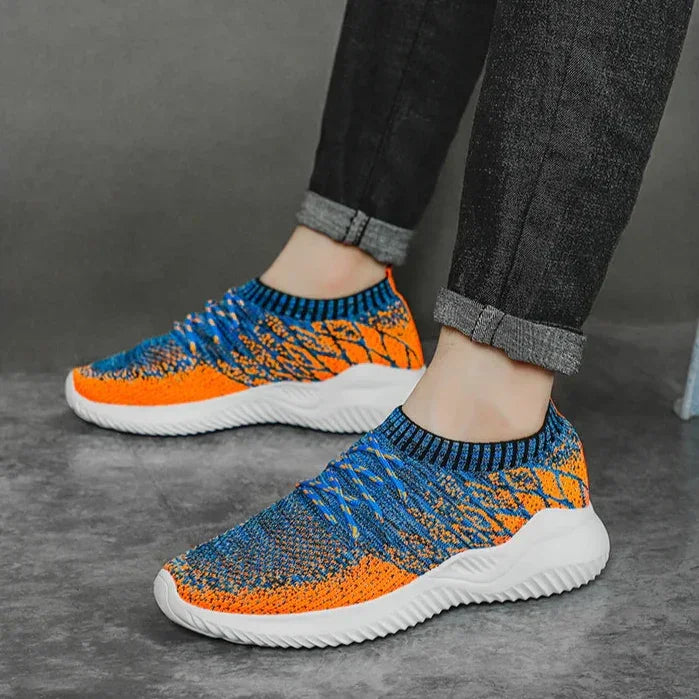 Rovelli men's knit sneakers in blue and orange with white soles, worn with rolled jeans