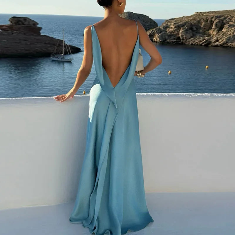 Woman in elegant light blue backless dress overlooking seaside view, Rovelli fashion