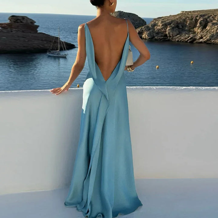 Woman in elegant light blue backless dress overlooking seaside view, Rovelli fashion