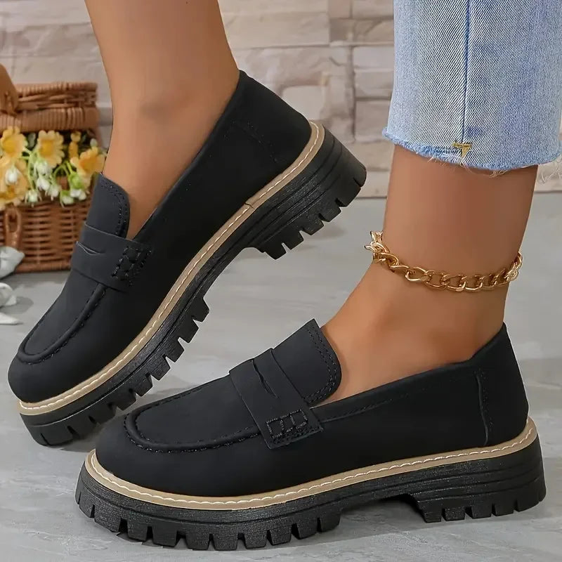 Woman wearing black chunky loafers with thick soles and gold ankle chain, Rovelli shoes