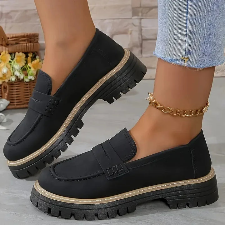 Woman wearing black chunky loafers with thick soles and gold ankle chain, Rovelli shoes