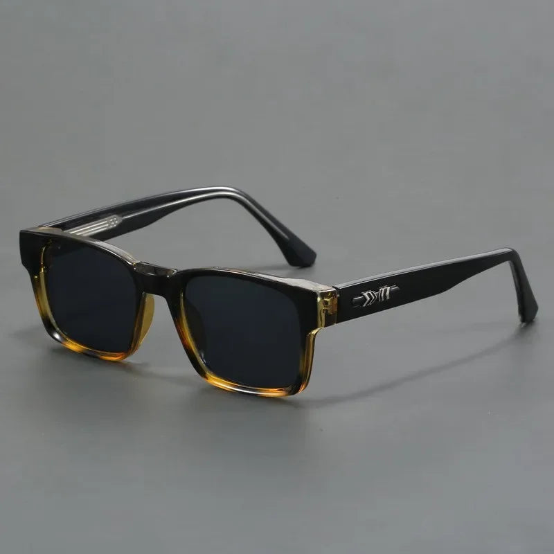 A pair of rectangular sunglasses with durable frames, black arms, and dark lenses. The frames feature a gradient from transparent brown at the bottom to black at the top, plus a silver arrow detail on the arms.