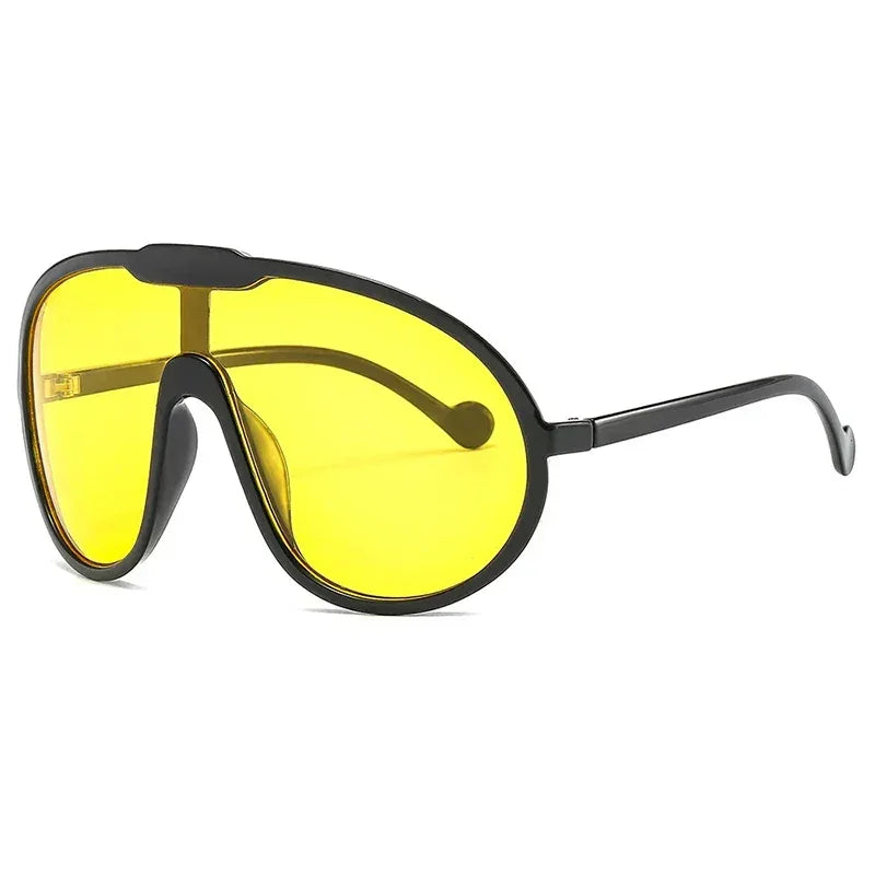 Black-framed oversized sunglasses with large, yellow-tinted lenses and curved arms offer UV400 protection—perfect for outdoor activities. Displayed on a white background.