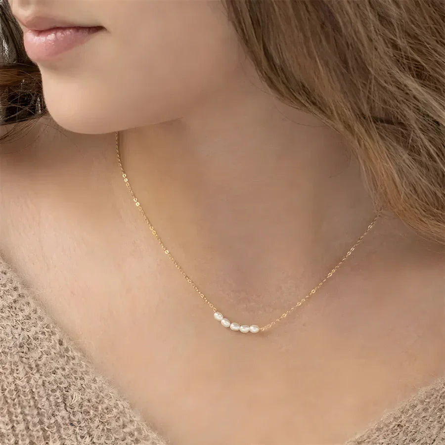 Woman wearing a Rovelli gold chain necklace with small white pearls