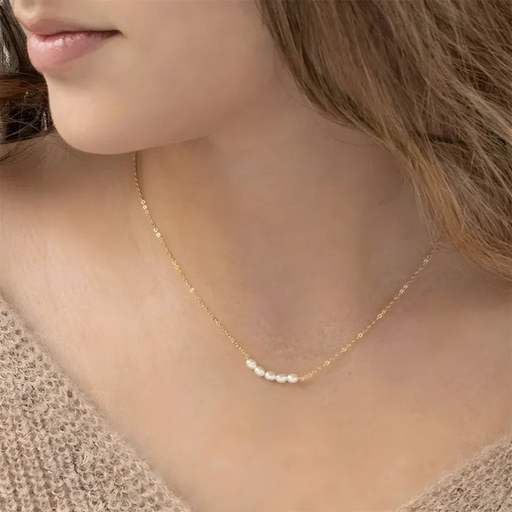 Woman wearing a Rovelli gold chain necklace with small white pearls