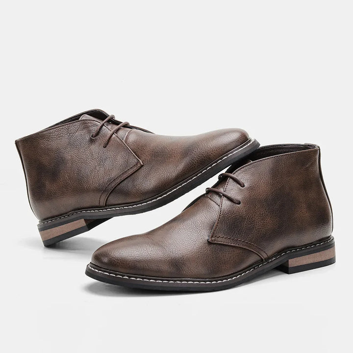 A pair of brown leather After-Ride Chukka boots with a low heel and black rubber sole, featuring a Western-inspired chukka silhouette, displayed against a plain white background.