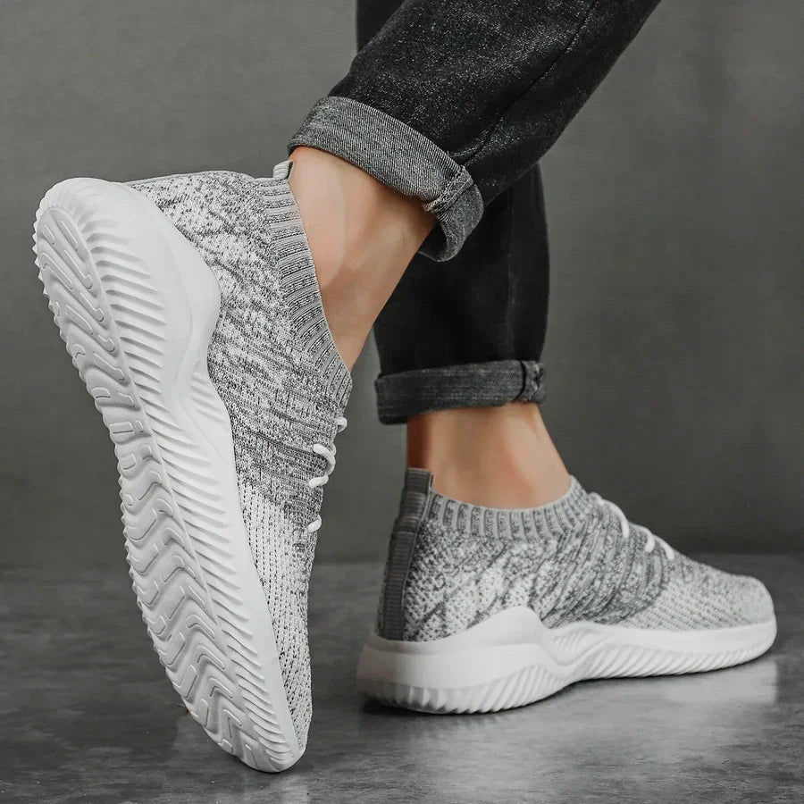 Rovelli casual grey knit sneakers with white soles, worn with rolled jeans on a grey floor