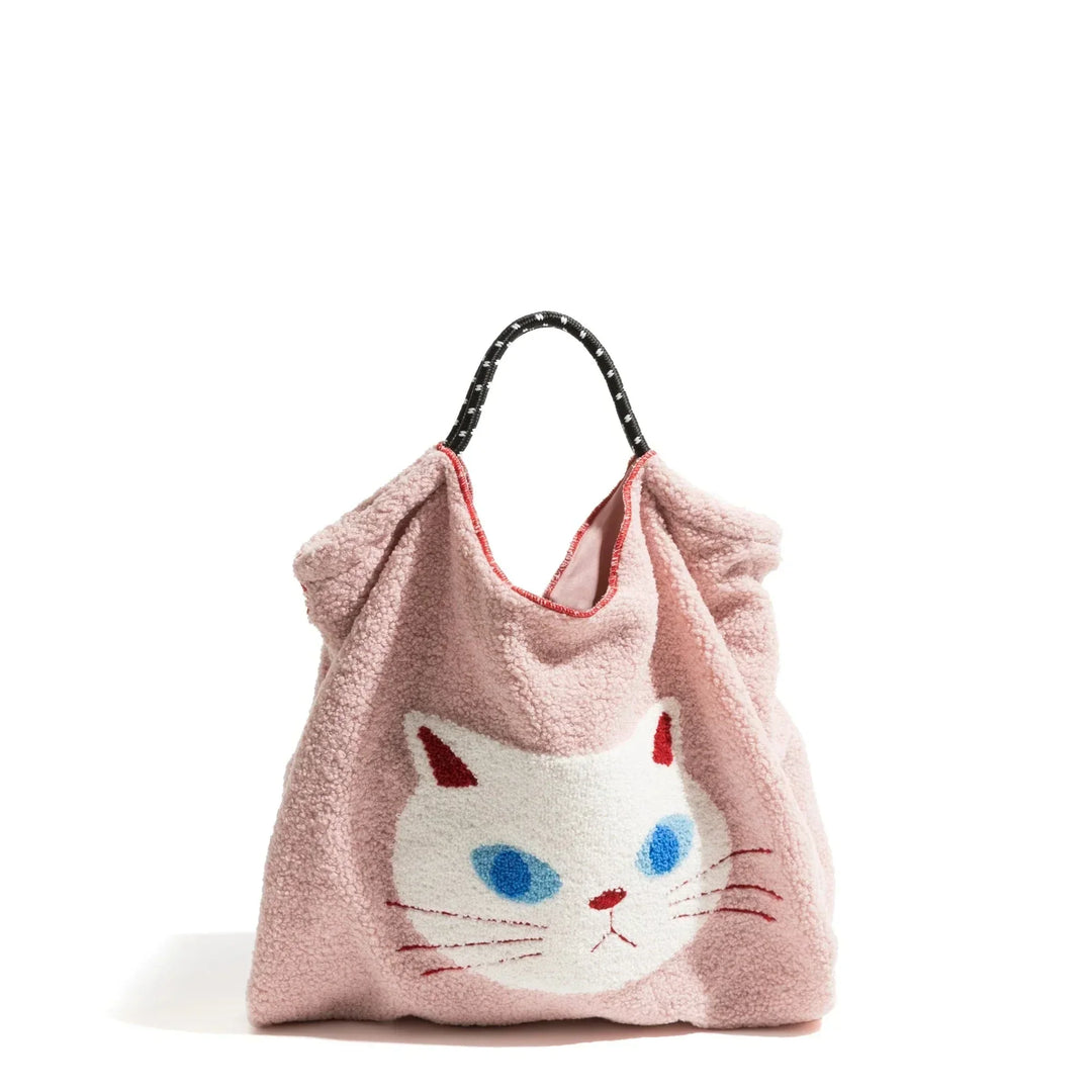 A pink faux fur handbag with a black handle, featuring a large white cat face with blue eyes, pink ears, and a red nose and mouth on the front—perfect for fans of animal pattern totes.