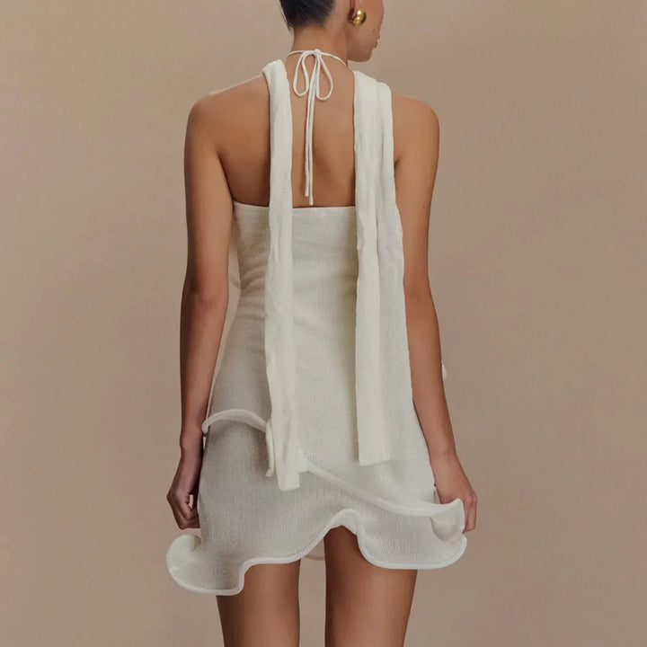 Back view of woman in a white halter mini dress with ruffle hem, Rovelli fashion