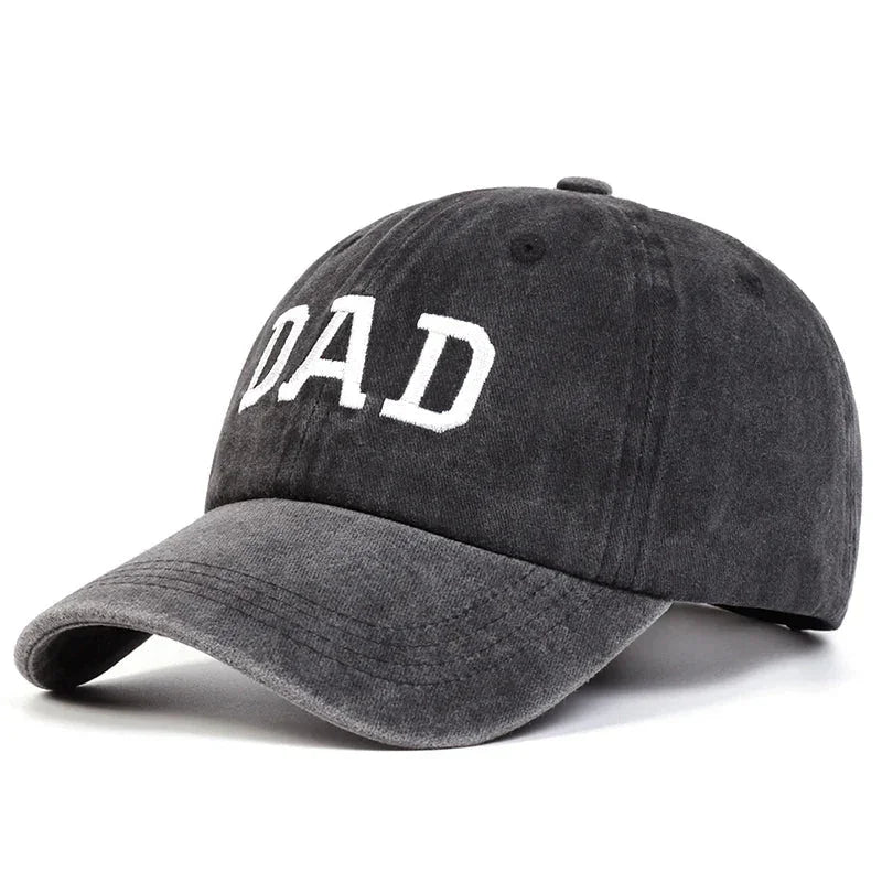 A dark gray embroidered cap with the word DAD in large white letters on the front, inspired by vintage streetwear and perfect as a classic Mom & Dad cap.