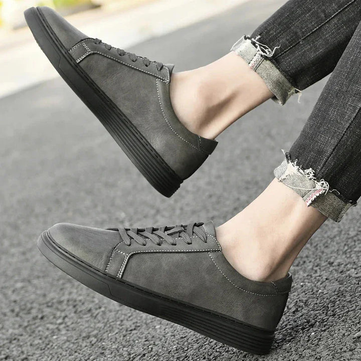 Rovelli gray casual sneakers with black soles, worn with rolled up jeans on pavement