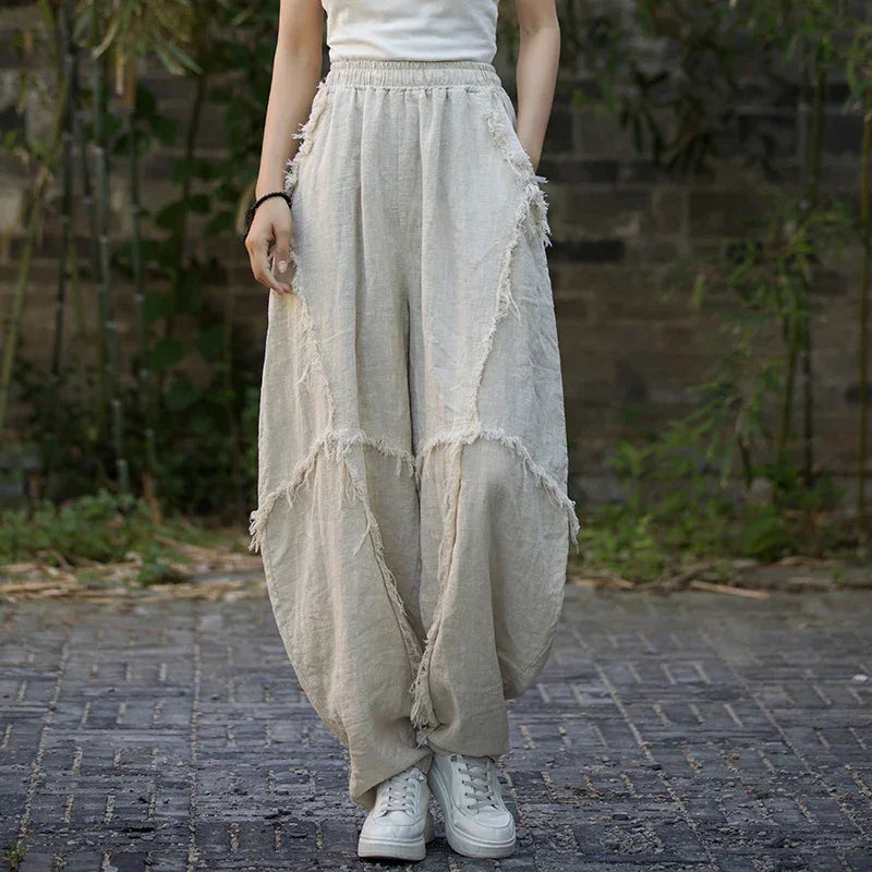 Woman wearing loose beige linen pants with fringed seams from Rovelli outdoors