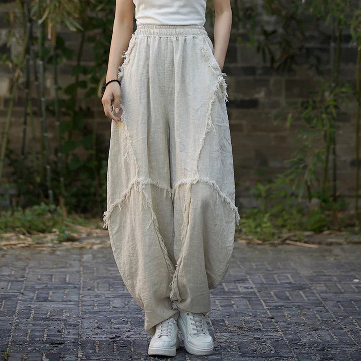 Woman wearing loose beige linen pants with fringed seams from Rovelli outdoors