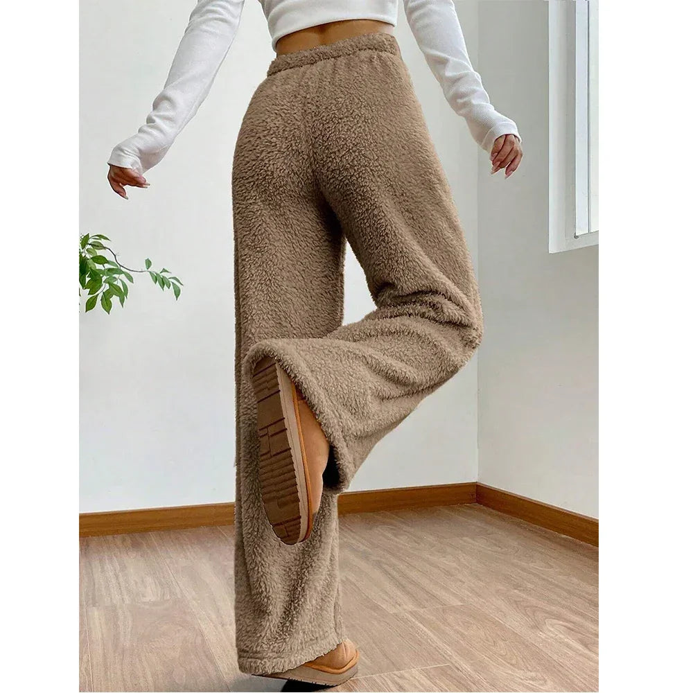 Woman wearing high-waisted brown fleece pants and boots in a bright room, Rovelli fashion