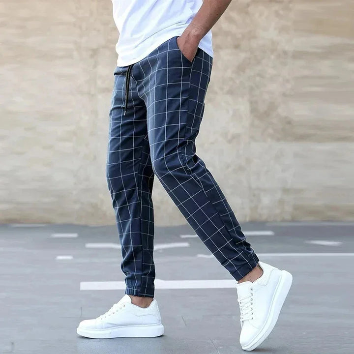 Man wearing Rovelli checkered jogger pants with white sneakers outdoors