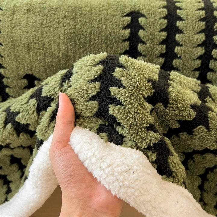 Hand holding a soft green Rovelli sherpa blanket with black geometric pattern
