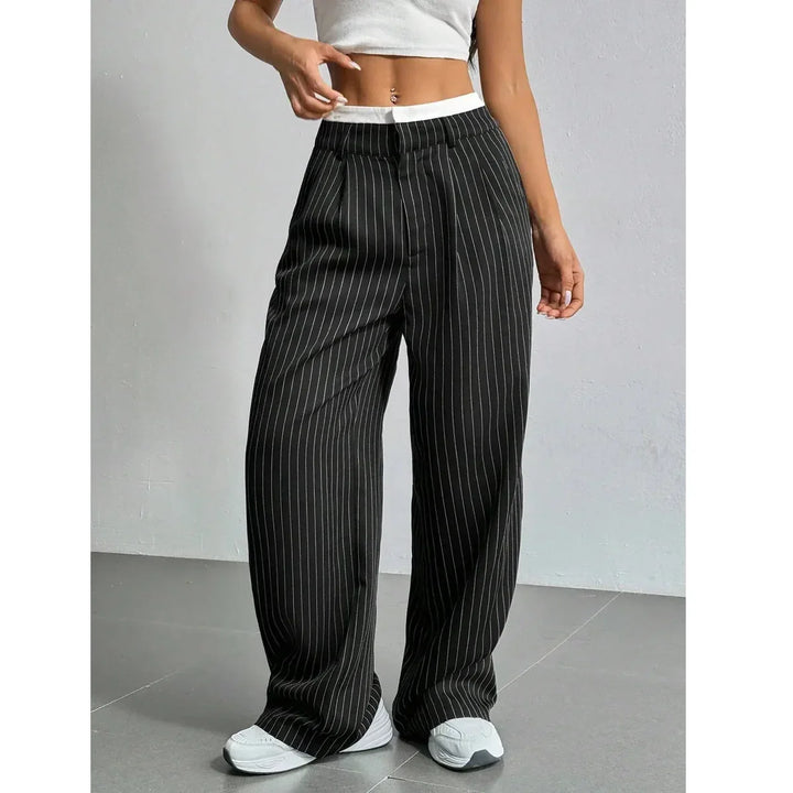 Woman wearing black pinstripe wide-leg pants from Rovelli, styled with white crop top and sneakers