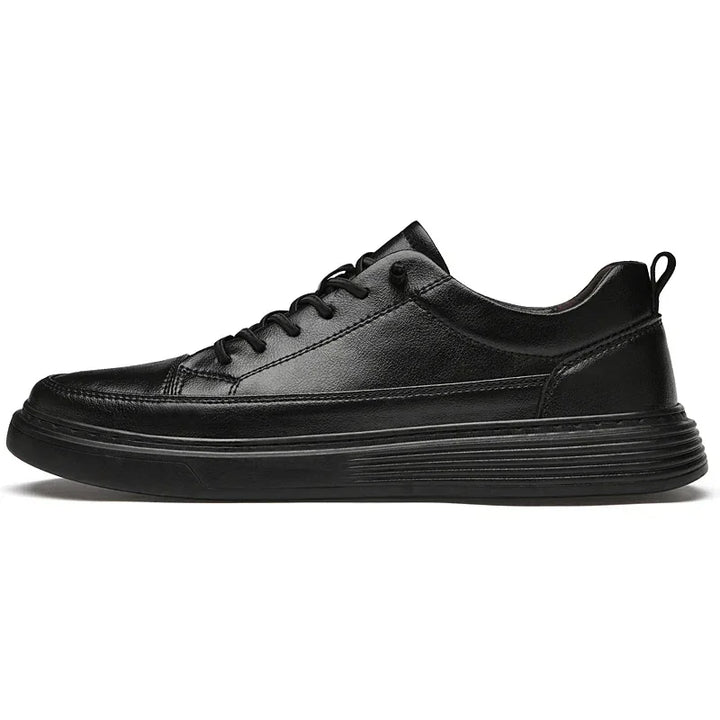 A black genuine leather sneaker with a low-top design, black laces, textured rubber sole, and pull tab at the heel, shown in a side profile view against a white background.