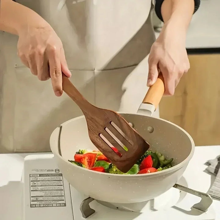 Person cooking vegetables in a white pan with a wooden spatula, Rovelli kitchenware