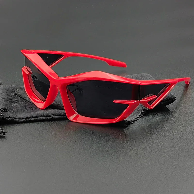 Red futuristic cycling glasses with geometric, angular frames and UV400 protection rest on a black cleaning cloth against a black background.