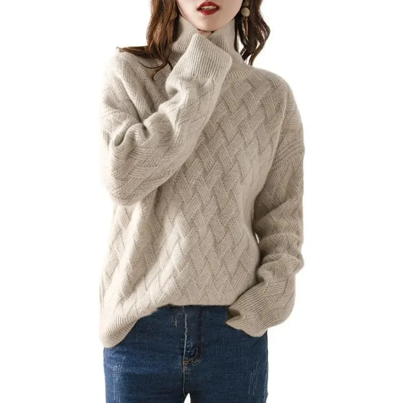 A woman wearing an ultra soft, cream-colored cable-knit turtleneck sweater and blue jeans, with one hand touching her collar and her hair partially covering her face.