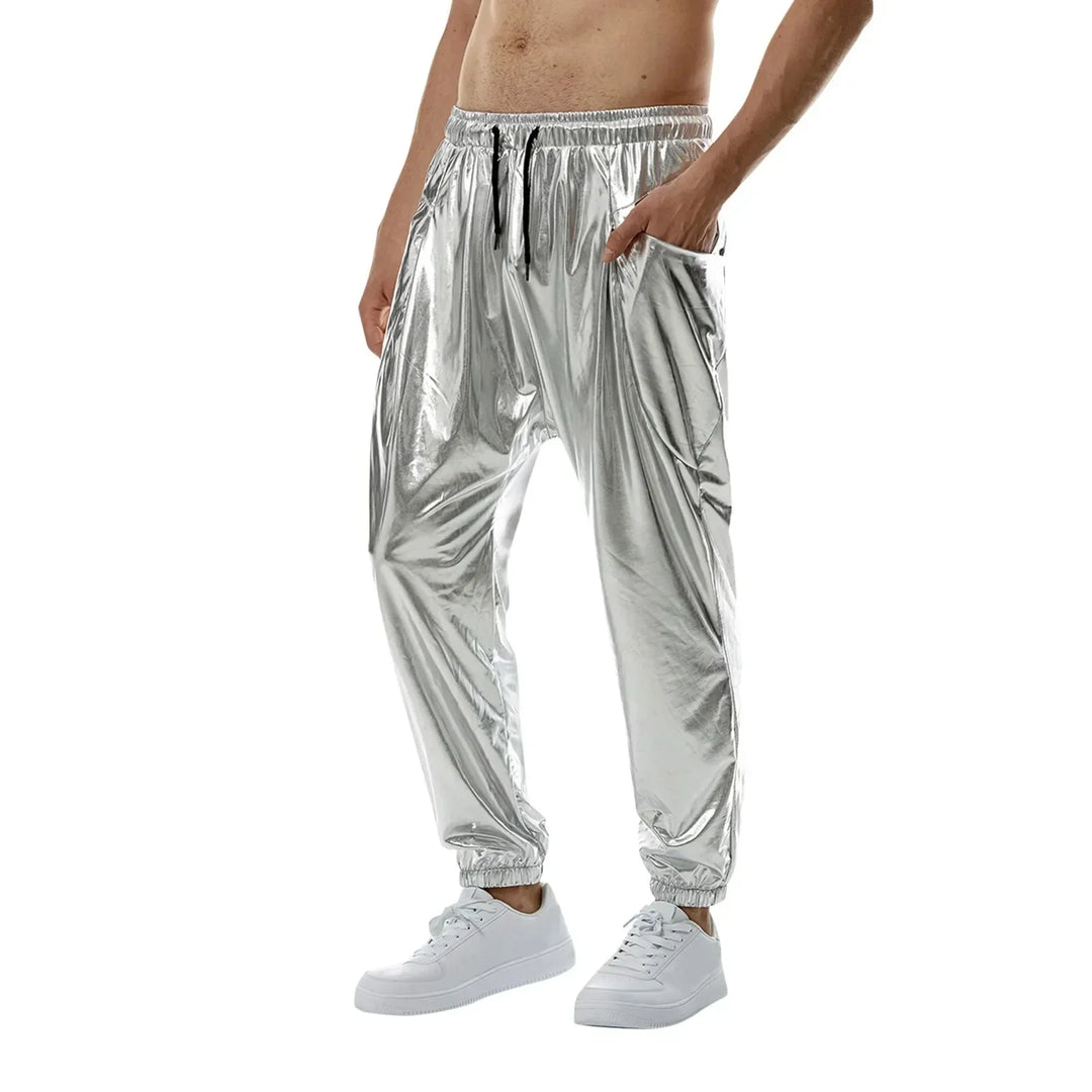 A person wearing lightweight metallic fabric jogger pants with an elastic waistband and drawstring, white sneakers, and no shirt, stands against a white background.