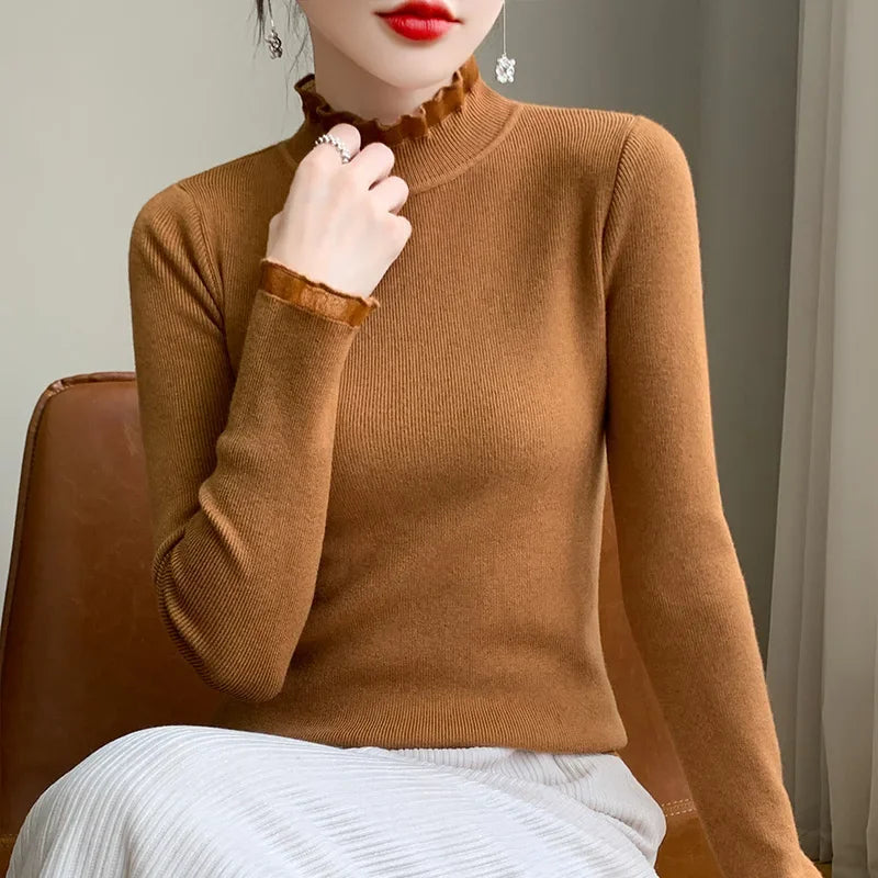 A woman wearing a fitted brown cashmere blend long-sleeve top with ruffled mock neck and cuffs, paired with a light-colored pleated skirt, sits on a brown chair. Her face is partially visible with red lipstick and dangling earrings.