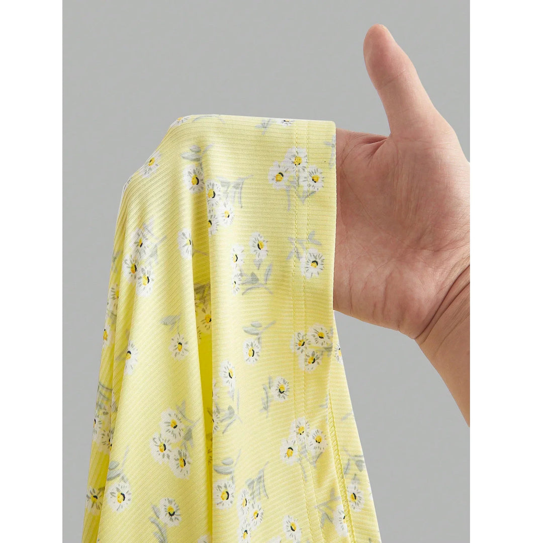Hand holding yellow floral fabric sample from Rovelli, soft stretch material.