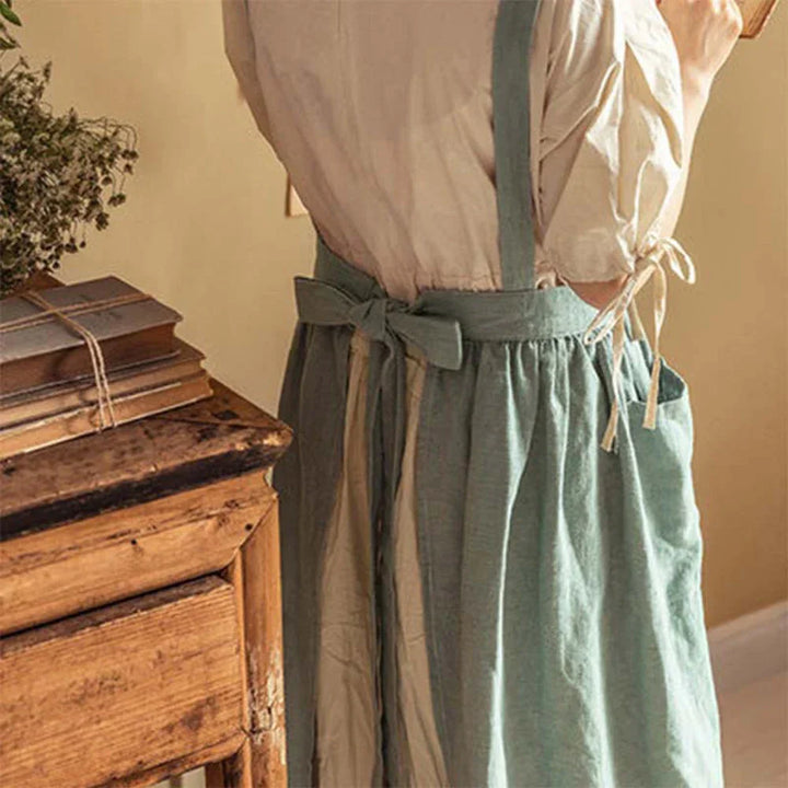 Vintage-style linen apron with bow, woman standing by rustic wooden desk, Rovelli home decor