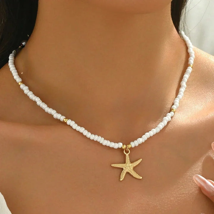 Woman wearing Rovelli white beaded necklace with gold starfish pendant